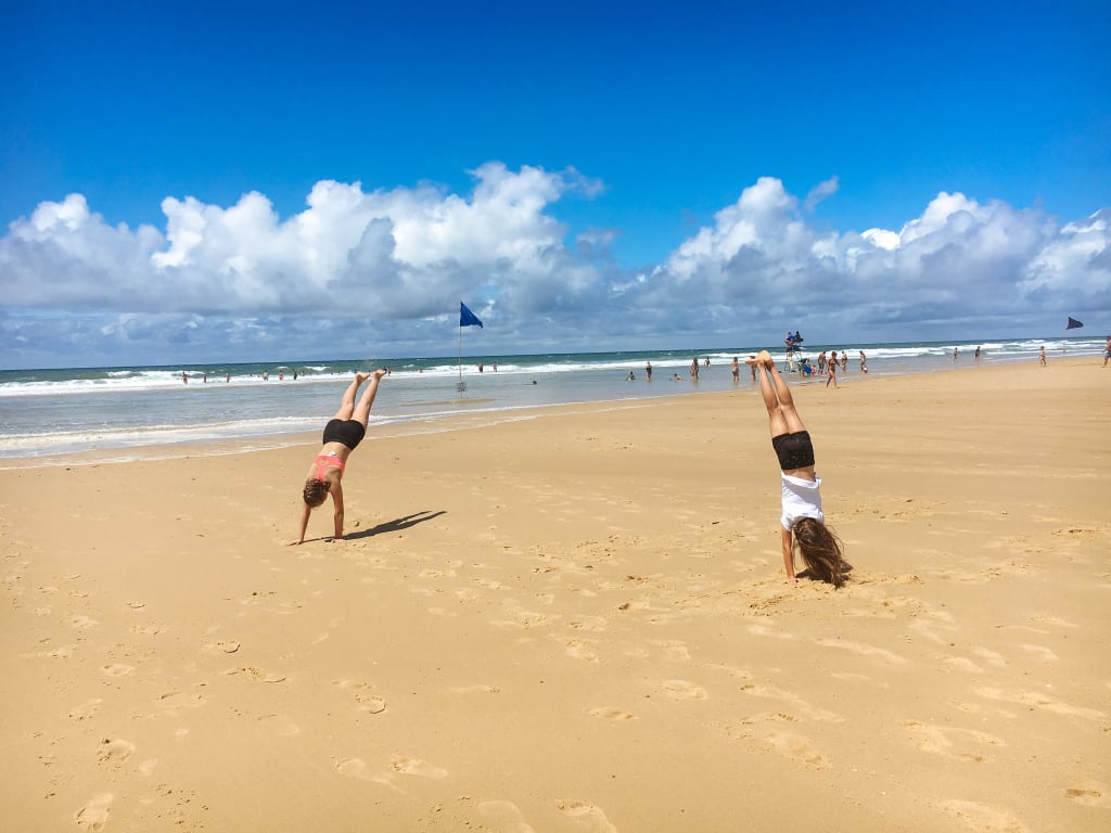 Persone che giocano sulla spiaggia sabbiosa della Baia di Arcachon sotto un cielo sereno.