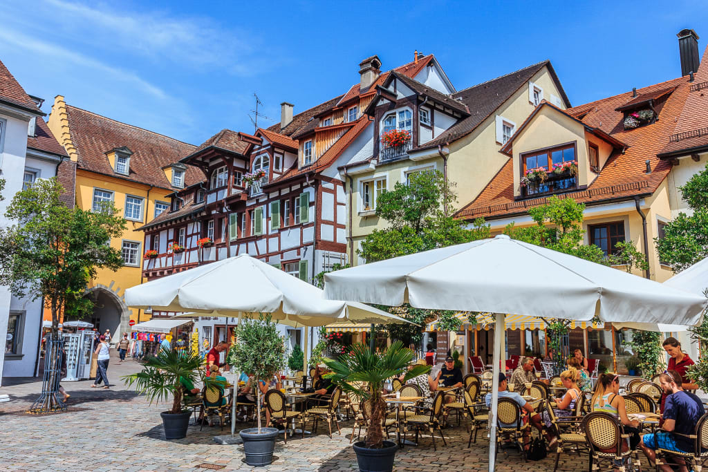 Turisti passeggiano e si rilassano in una piazza affollata con caffè e negozi, tour in bici classico da Friedrichshafen