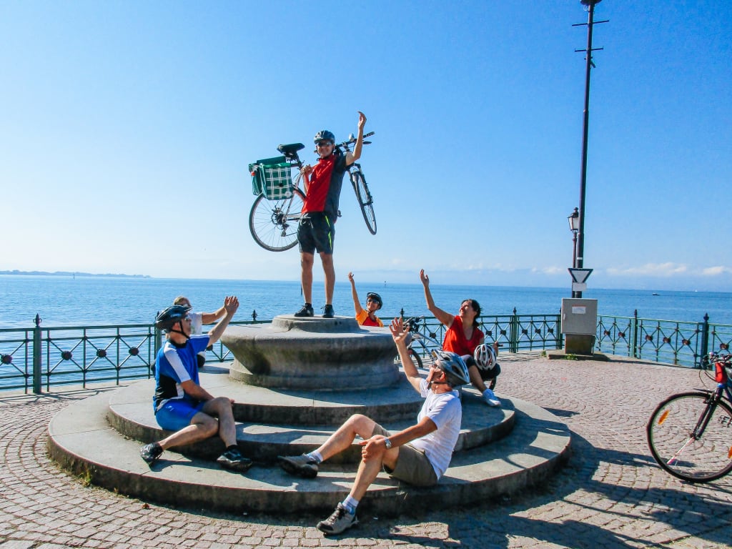 Ciclisti che posano con bici davanti a una statua, Lago di Costanza, Germania