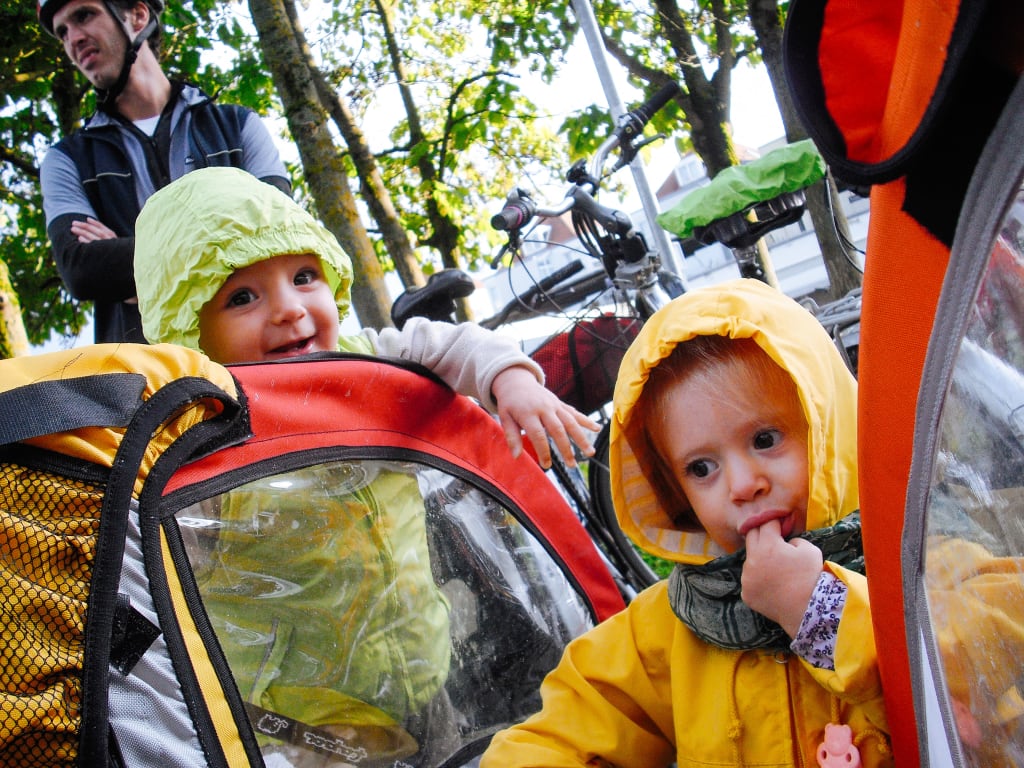 Bambini seduti in un carrellino da bici durante una vacanza in bicicletta per famiglie, cicloturismo sicuro