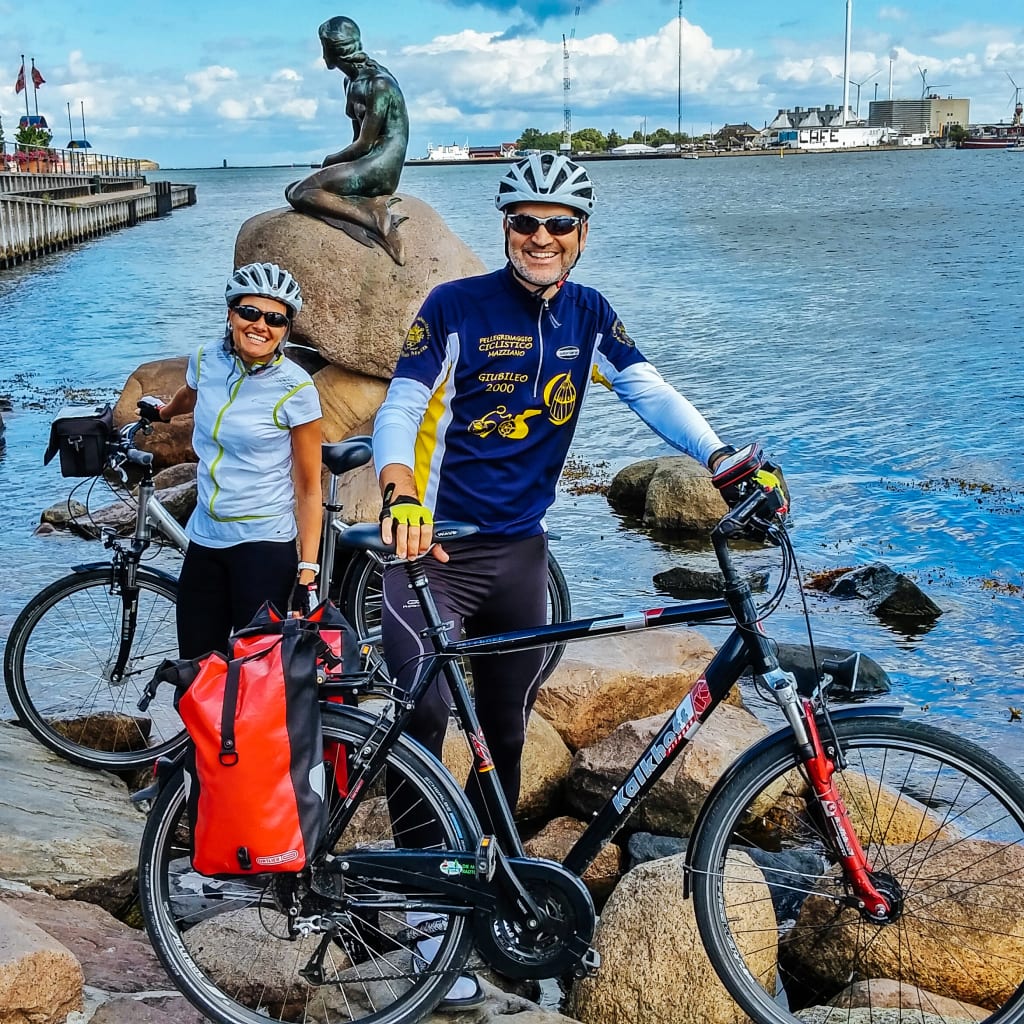Ciclisti in posa vicino alla statua della Sirenetta, Copenaghen, Danimarca