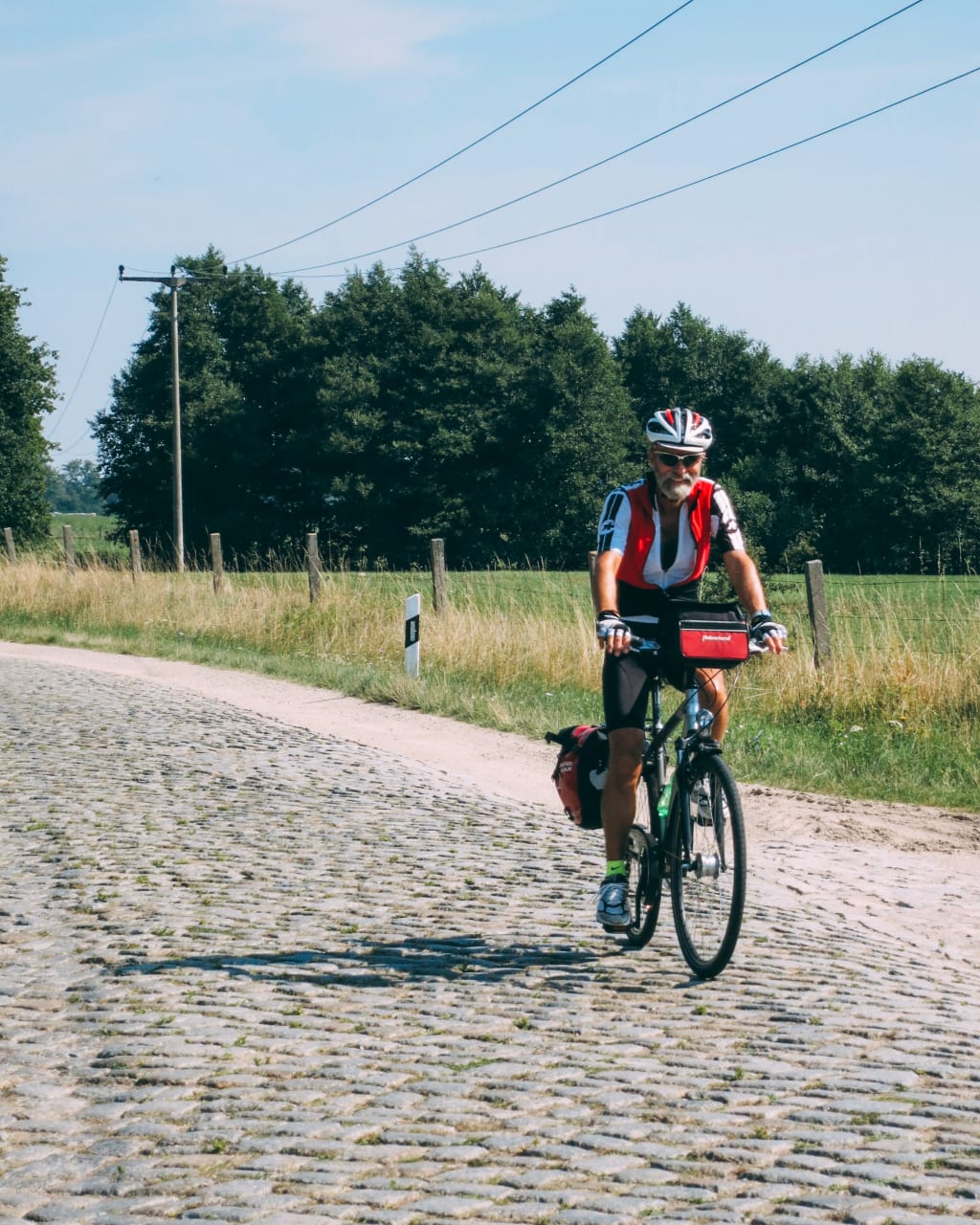 Ciclista su un sentiero di ciottoli con campagna verde sullo sfondo.