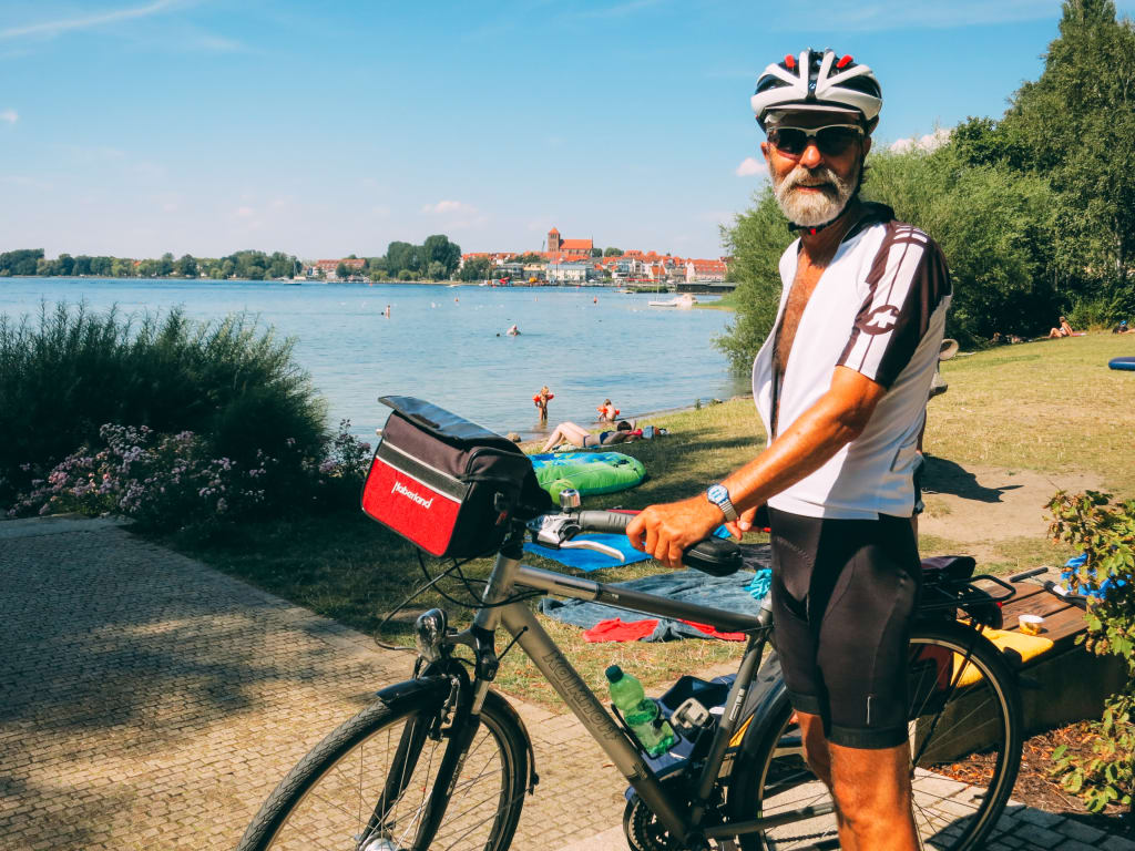 Ciclista in sosta con la sua bici sulla ciclabile nella regione dei laghi del Meclemburgo.