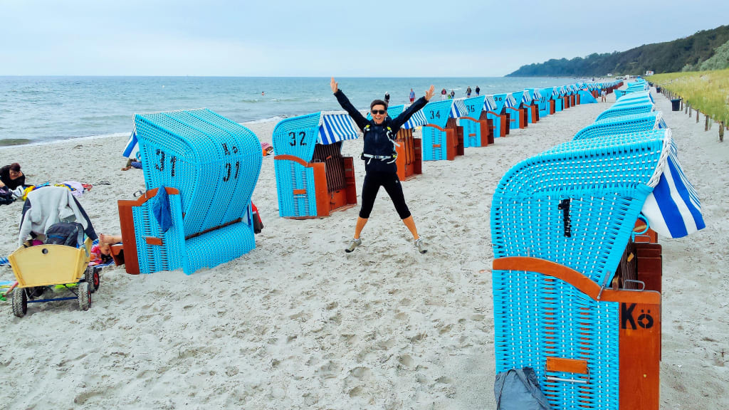 ciclista su una spiaggia del Mar Baltico circondato da cabine colorate