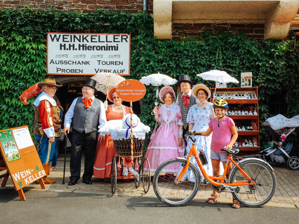 Ciclista in posa con gruppo locale in abiti folkloristici in Germania