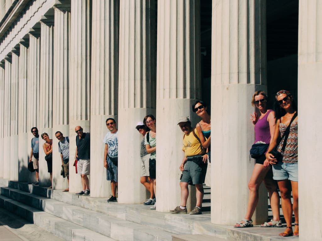 Gruppo di turisti tra le colonne antiche del Tempio di Apollo, Atene, Grecia
