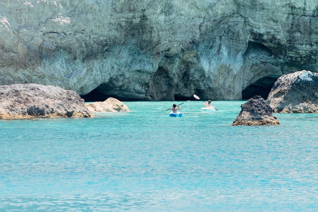 People swim in the turquoise waters and caves between the rocks