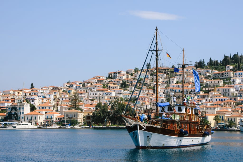 Holzsegelboot vor Anker in der Nähe einer Küstenstadt mit traditionellen Häusern
