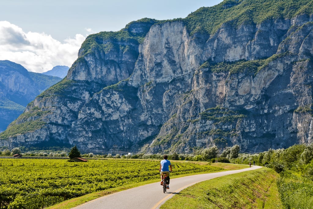 Cyclist on a bike path with mountain views near Rovereto, Italy.