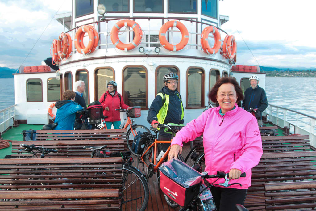 Group of cycle tourists with "Girolibero" bikes on the deck of a boat, excursion on Lake Garda, bike and boat