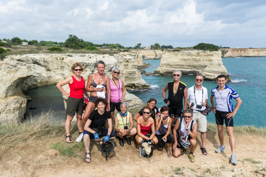 Gruppo di escursionisti in posa davanti alla Grotta della Poesia a Roca Vecchia, Puglia, trekking in Salento