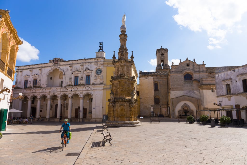 Cicloturista visita il centro storico, museo Palazzo di Città, guglia dell'Immacolata, piazza Salandra, Nardò, Puglia