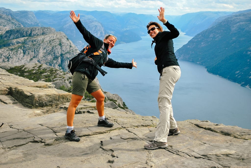 Coppia di turisti in posa su Preikestolen con vista sul Lysefjord, Norvegia