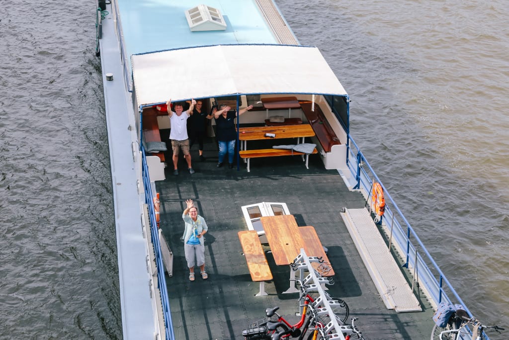 Tourists wave from the outside deck of the sailing barge