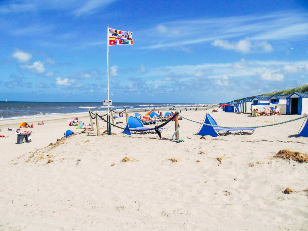 Spiaggia sabbiosa con barche da pesca e bandiera a Texel, isola dei Paesi Bassi.