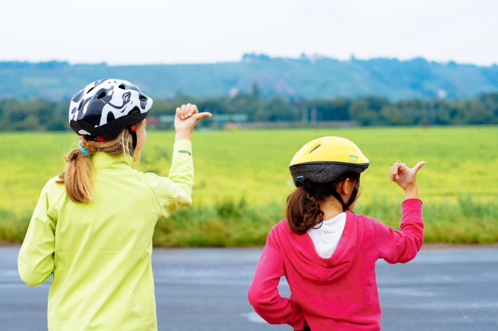 Bambini in casco da bici che indicano il paesaggio lungo un fiume, esperienza di viaggio in famiglia nella natura