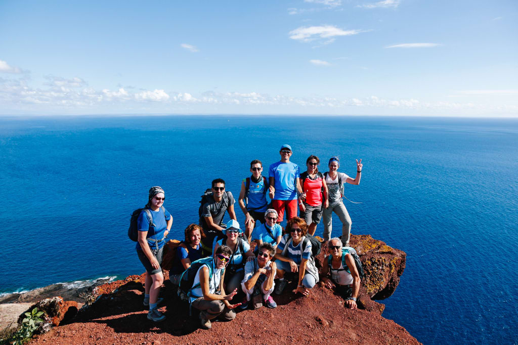 Gruppo di escursionisti su una scogliera rocciosa con vista sul mare e Tenerife in un viaggio a piedi con Girolibero Zeppelin
