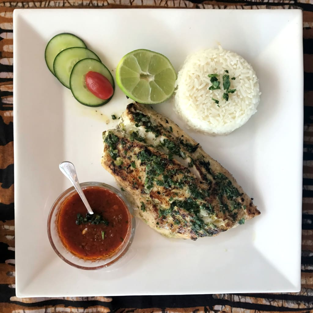 Piatto di thieboudienne, riso e pesce tipico senegalese, servito con verdure e salsa piccante