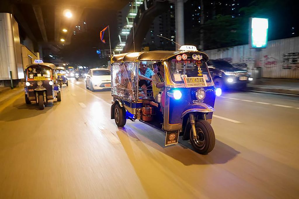 Tuk tuk che percorre le strade di Bangkok di notte durante un city tour.
