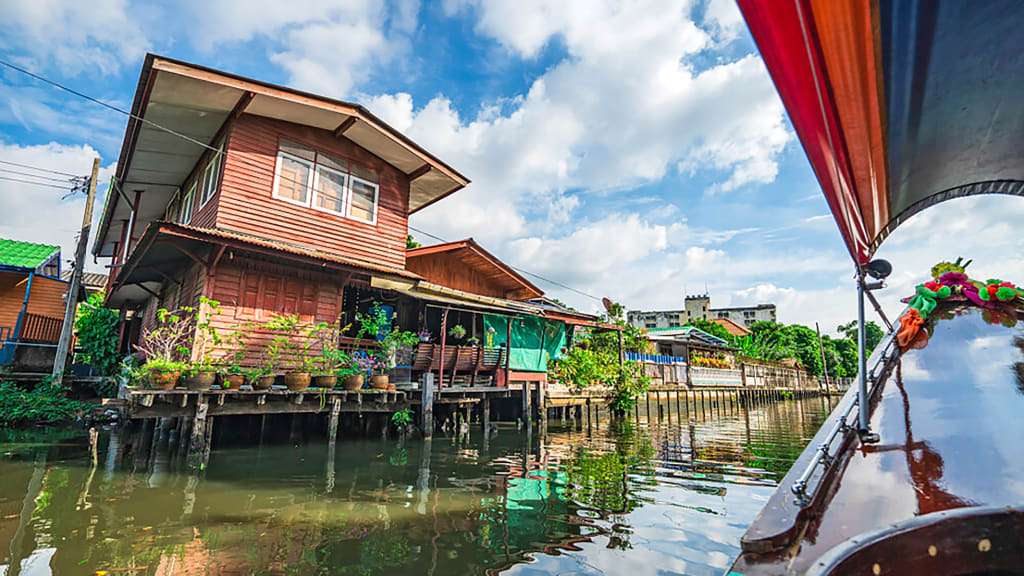 Case tradizionali su palafitte viste dal long-tail boat nei canali di Bangkok.