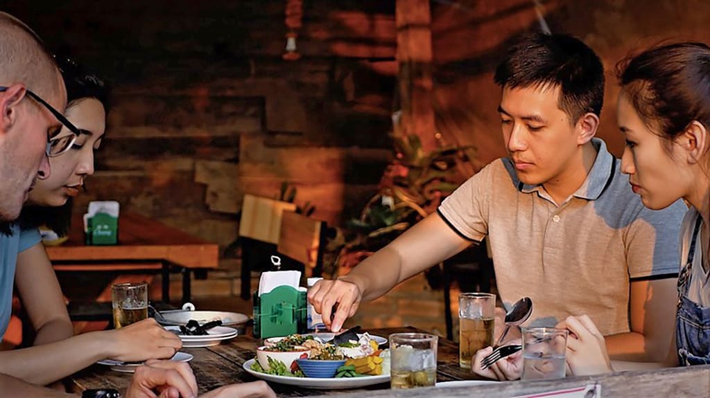 Turisti che cenano in un ristorante tipico thailandese degustando piatti locali.