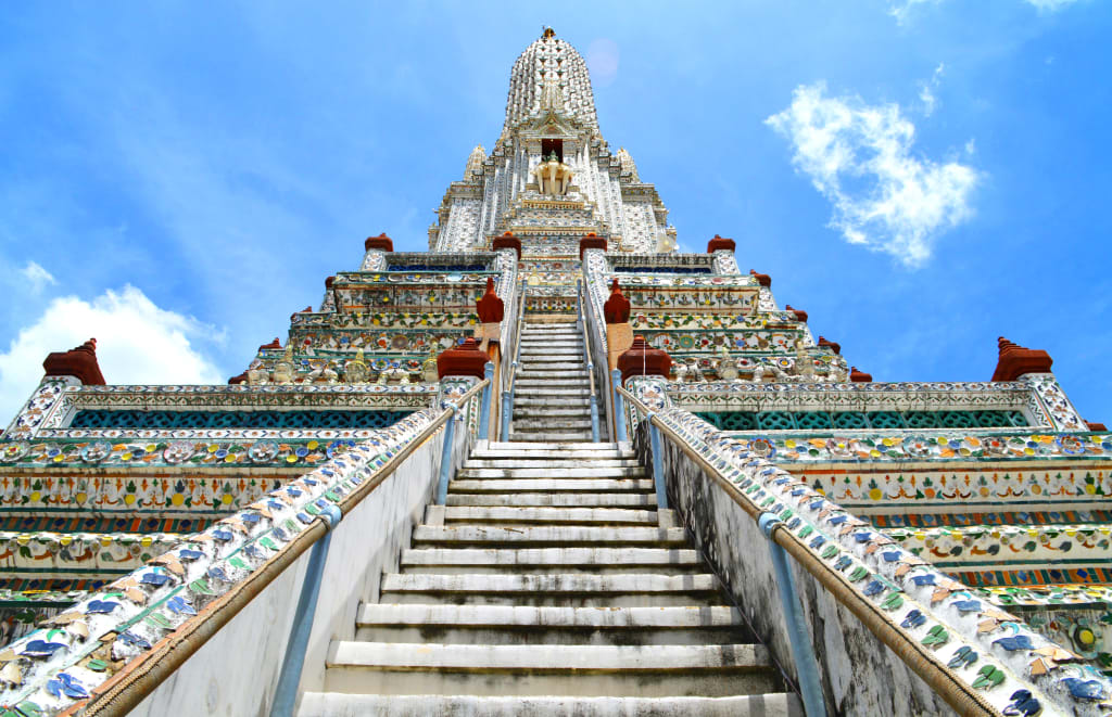 Scalinata monumentale del Wat Arun a Bangkok con decorazioni in ceramica colorata.