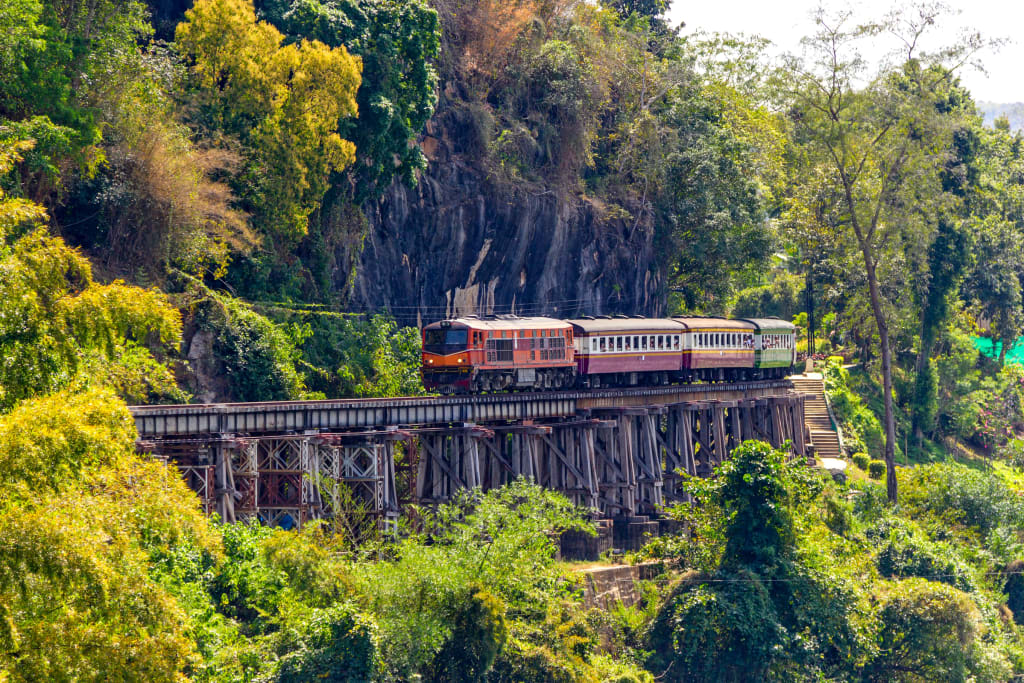 Treno che attraversa il ponte ferroviario del Death Railway a Kanchanaburi immerso nella giungla.