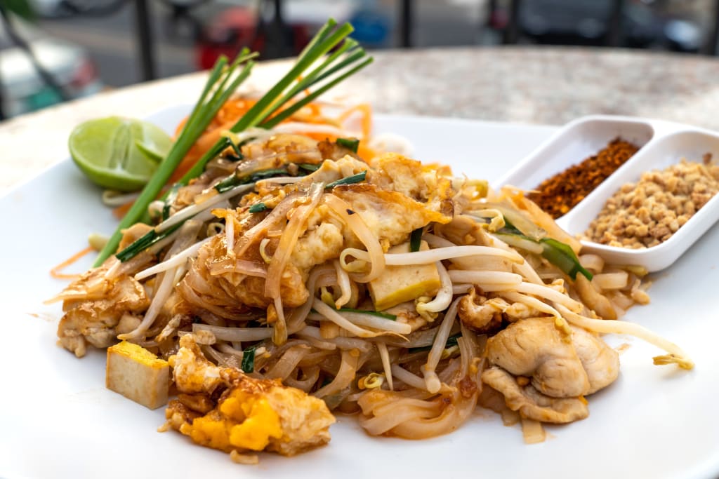 Piatto di Pad Thai tradizionale con gamberi, lime e arachidi, tipico della cucina thailandese.