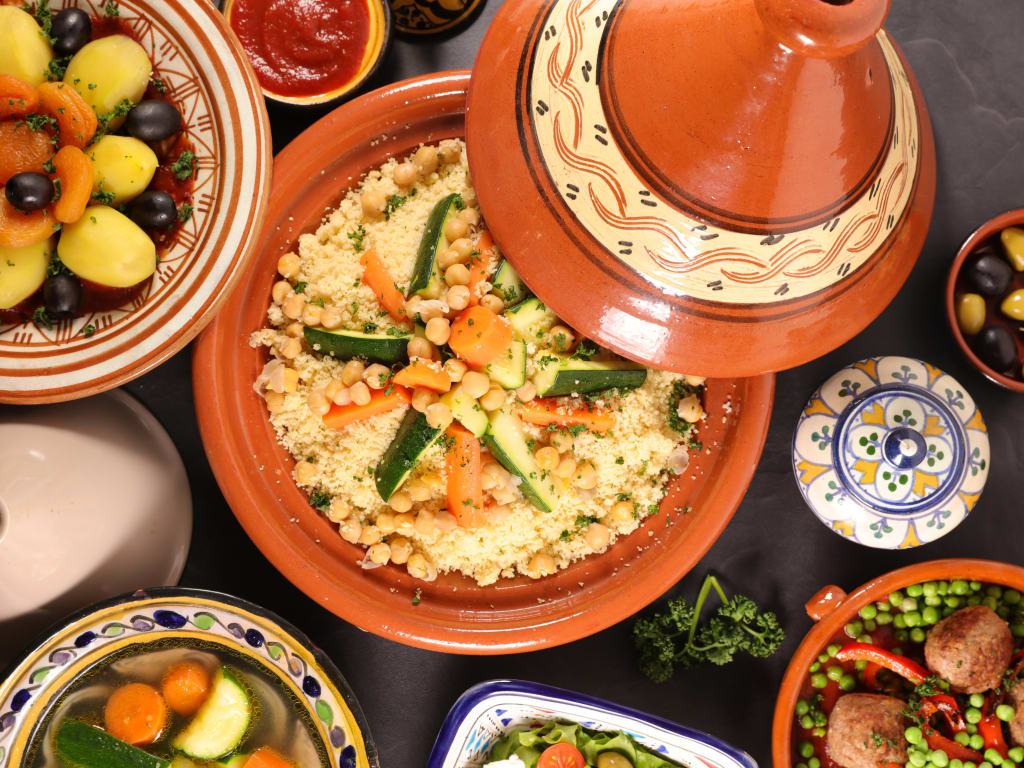 Tavola ricca di piatti tradizionali tunisini, tra cui tajine e couscous.