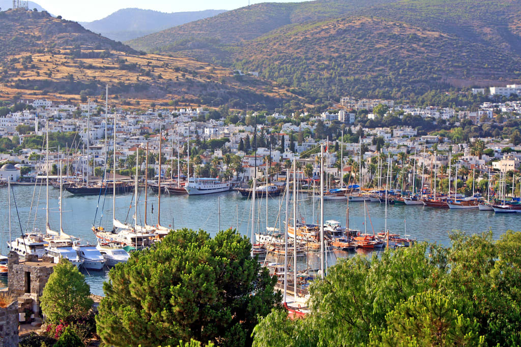 Città costiera, fiume con barche, colline e case bianche sullo sfondo, Turchia