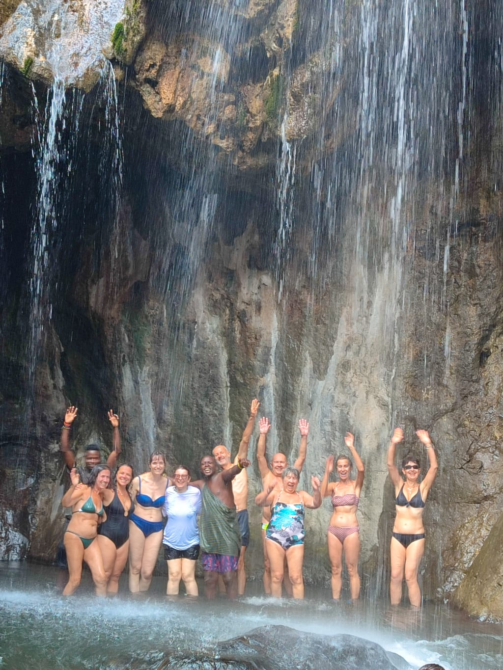 Gruppo di viaggiatori che si rinfresca sotto una cascata