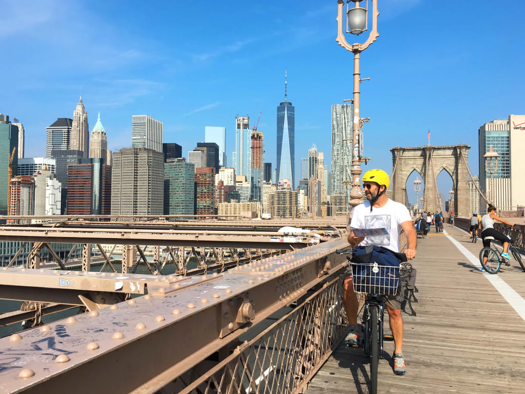 Ciclista sul ponte di Brooklyn con lo skyline di Manhattan sullo sfondo, New York, USA.