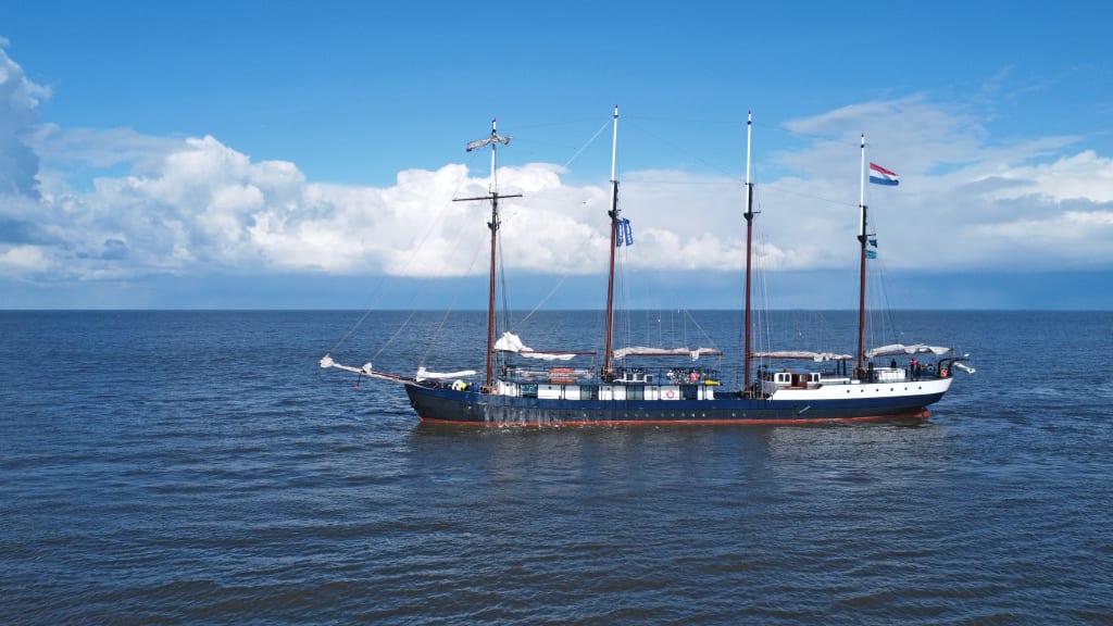 Schooner sailing on the North Sea with blue sky and clouds on the horizon.