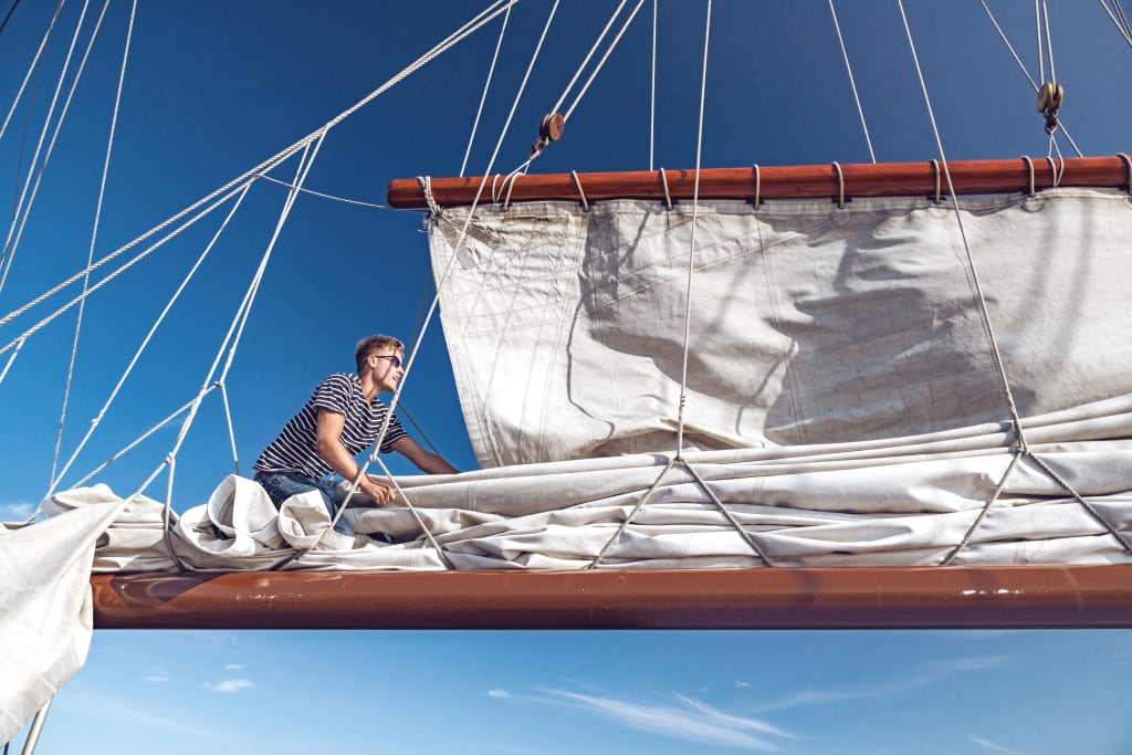 Sailor adjusting the sails on a traditional Dutch schooner.