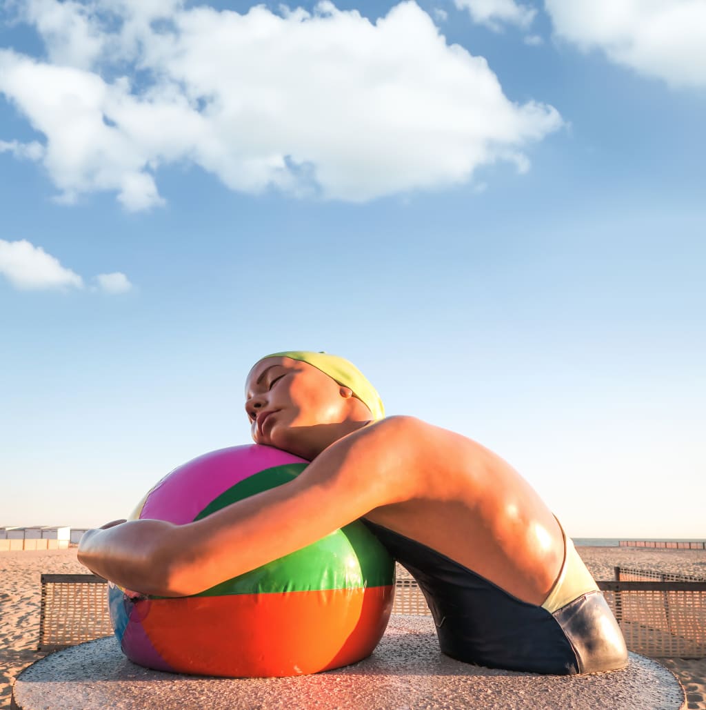 Scultura con donna che si appoggia su una grande palla colorata, parchi tematici in Belgio, tour delle Fiandre