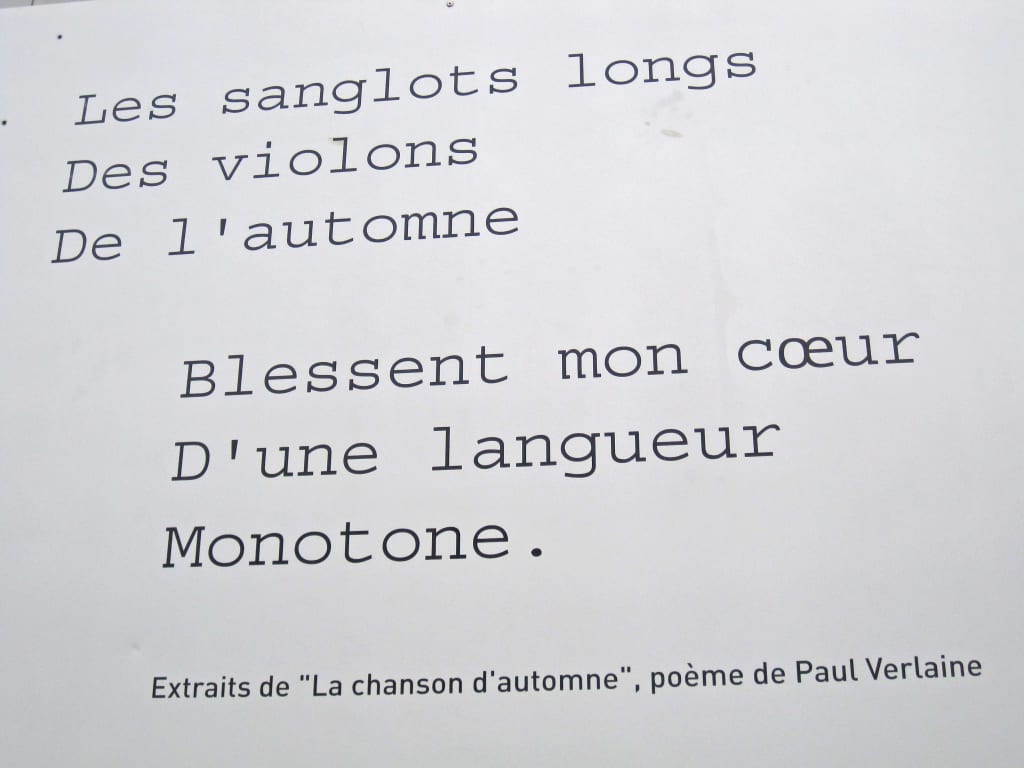 Versi poetici di Paul Verlaine incisi su pannello informativo lungo un percorso culturale in Normandia