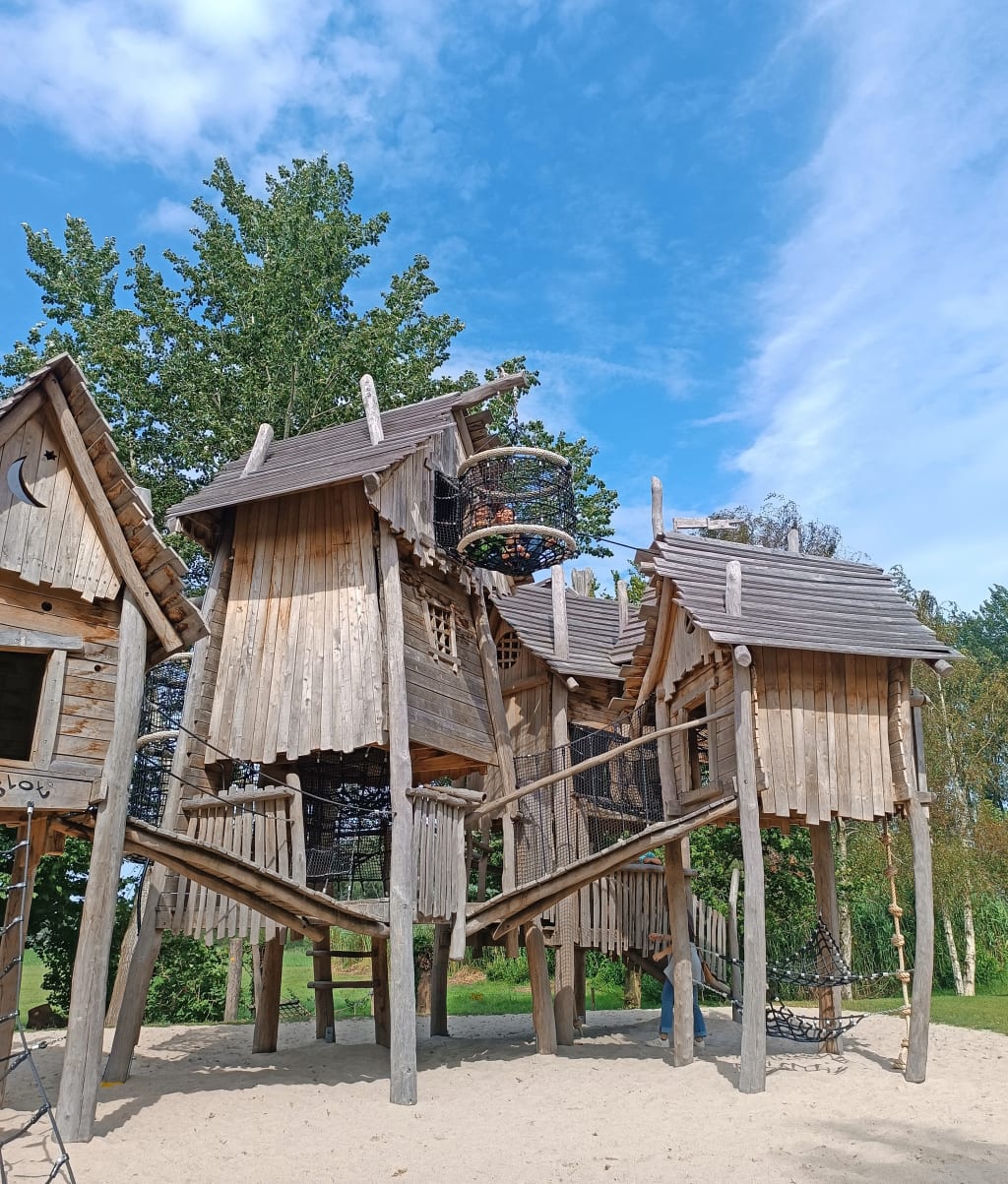 Parco giochi in legno per bambini nei Paesi Bassi, area ludica immersa nel verde ideale per viaggi in famiglia.