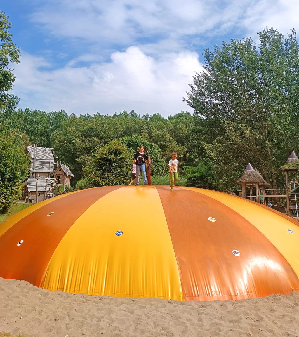 Bambini che giocano su una grande struttura ludica arancione in un parco urbano dei Paesi Bassi, esperienza all’aria aperta durante una vacanza in famiglia.