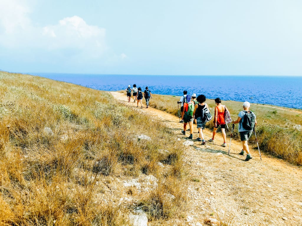 Escursionisti su un percorso costiero con vista mare nel Salento.