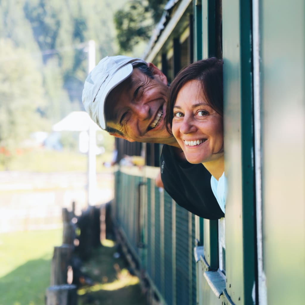 Coppia affacciata al finestrino del treno panoramico in Romania, viaggio organizzato Girolibero tra paesaggi rurali e montagne dei Carpazi