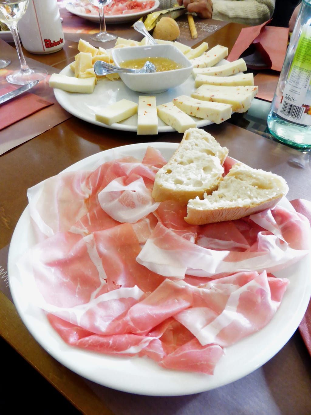 Tagliere di prosciutto crudo, formaggi e pane tipico, specialità italiane.