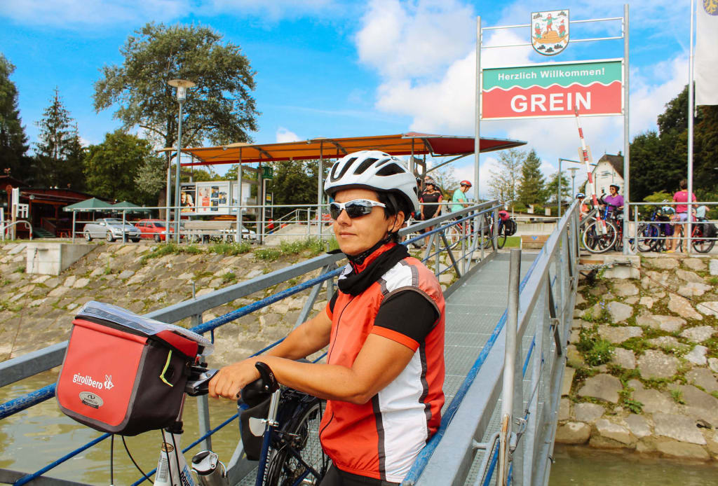 Ciclista risalendo sulla barca nel Danubio, Austria