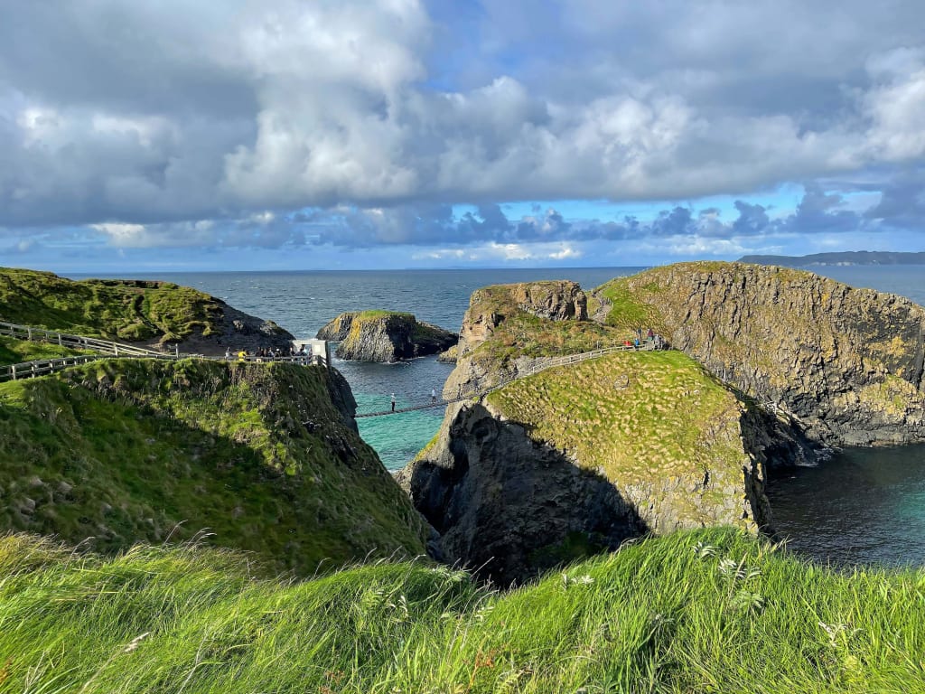Ponte su scogliere verdi lungo la costa dell'Irlanda del Nord, con vista sull'oceano, Giant's Causeway tour con "Girolibero"