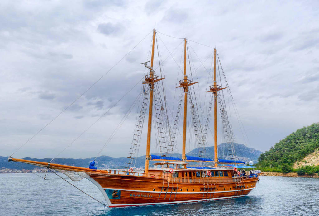 Barca a vela Thalassa ormeggiata in una baia circondata da colline verdi a Lefkada, Grecia.