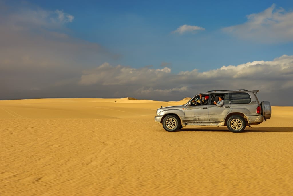 Fuoristrada durante un safari nel Deserto Occidentale dell'Egitto tra le dune di sabbia.