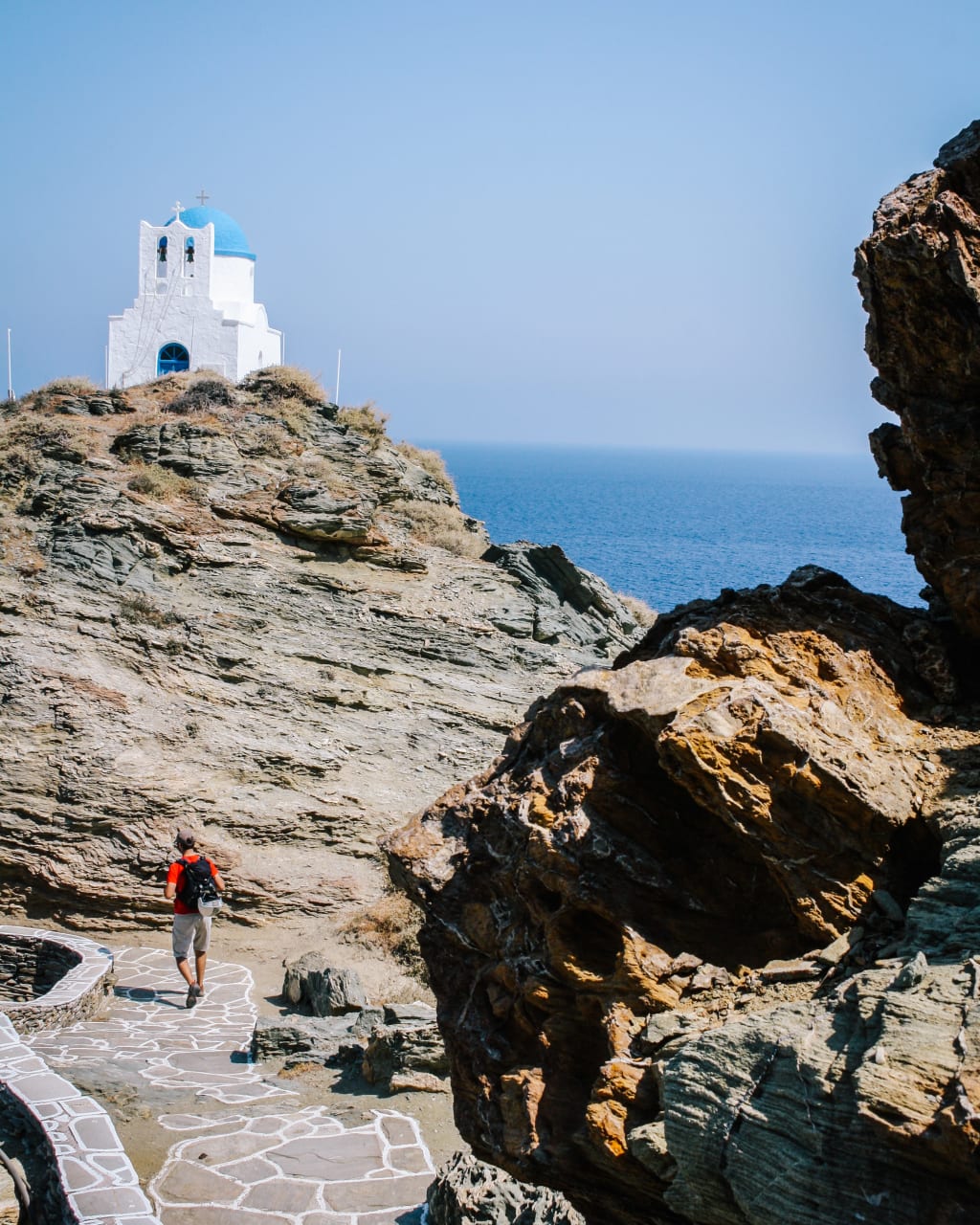 Escursionista su sentiero costiero, Cappella bianca di Panagia Poulati con vista sul mare, Sifnos, Grecia