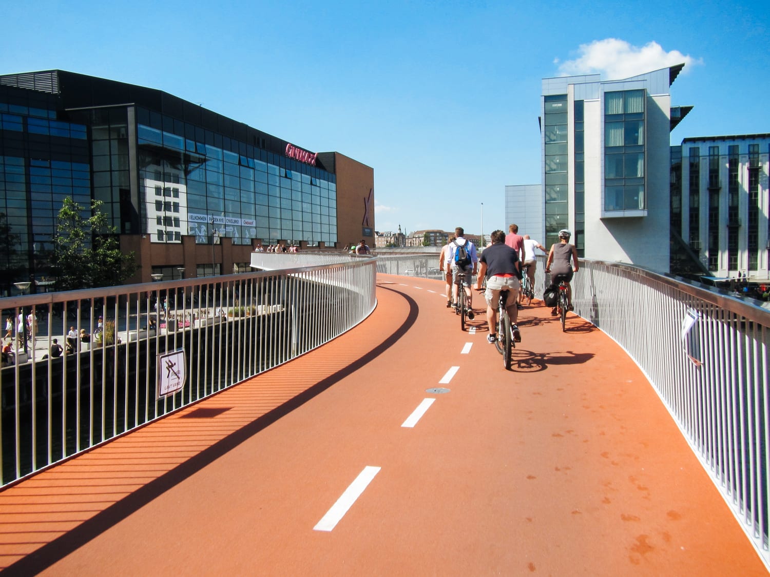 Ciclisti percorrono il ponte ciclabile rosso "Cykelslangen" sopra l’acqua nel centro di Copenaghen, Danimarca