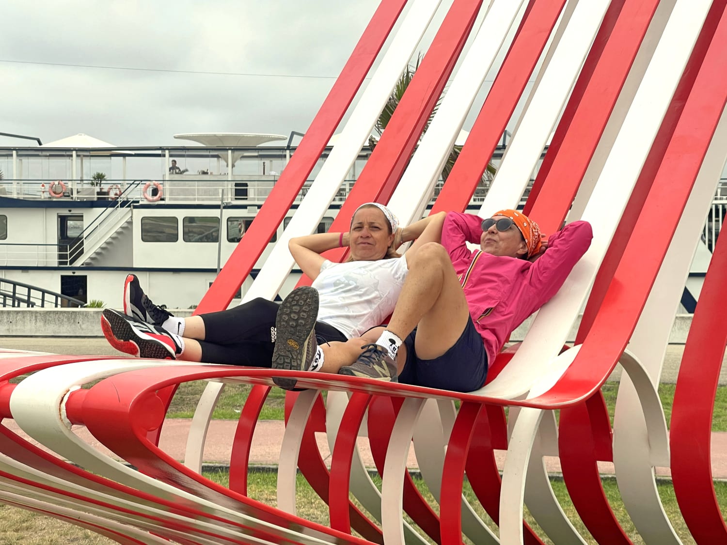Cicliste in viaggio con Girolibero rilassate su grandi sculture urbane rosse a forma di poltrona