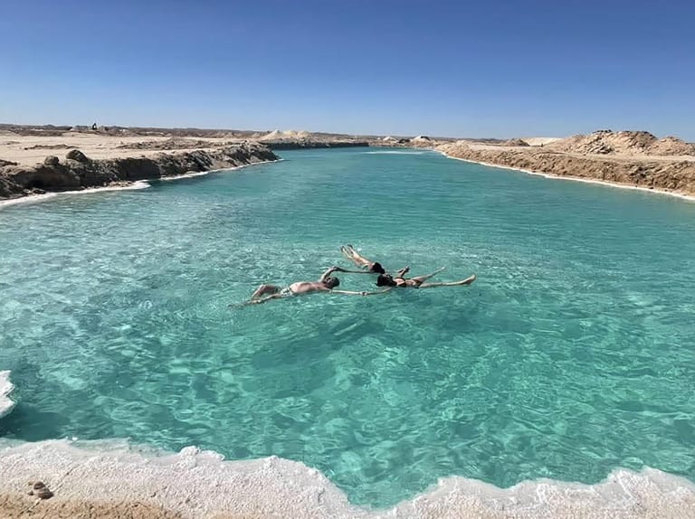 Laguna turchese nel deserto egiziano con persone che nuotano