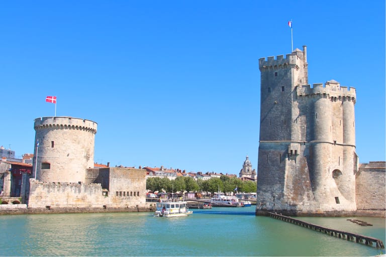 Torre e porto antico a La Rochelle con cielo azzurro e mare calmo, Francia